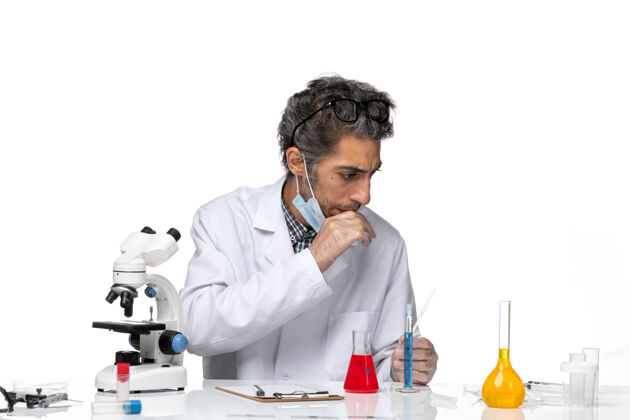 外套前视图穿着白色医疗服的中年科学家围坐在桌子旁 拿着解决方案套装化学研究