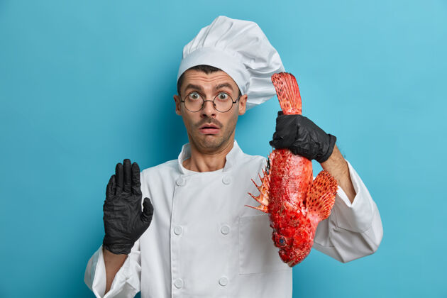 负惊呆了的厨师拿着大鱼 用海鲜做饭 屏住呼吸做停顿手势 给食物提示 有很好的烹饪技巧美味烹饪眼镜