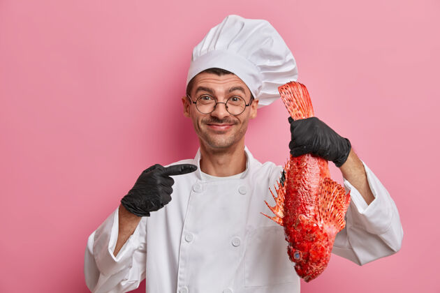 海洋快乐的专业男厨师点着大红海鲈鱼 去做美食 身着白色制服 头戴面包师帽鱼制服穿
