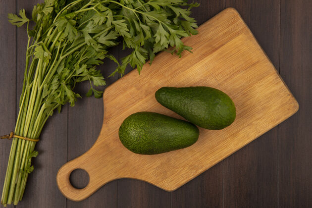 素食木质厨房板上亮绿色鳄梨的俯视图 欧芹被隔离在木质墙壁上美食木材蔬菜