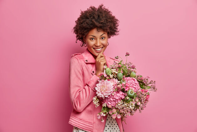 姿势快乐温柔的美国黑人年轻女子 精神饱满 收到漂亮的鲜花 享受美好的礼物 笑容灿烂 在室内摆姿势快乐的老师在知识日收到学生们的花束春天携带非洲