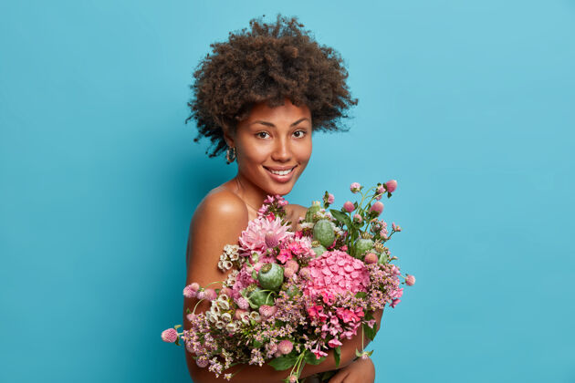 美丽好看的卷发女人得到自然的礼物 携带美丽的花束立场花束花