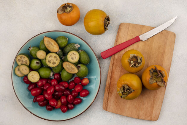 柿子蓝色盘子上放着美味的新鲜凤梨 灰色墙壁上放着小刀 木制菜板上放着柿子飞珠美味视野