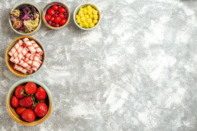 盖顶视图新鲜的红色草莓和糖果的白色表面浆果红色糖果美味水果盘子