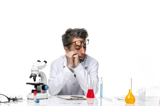 前面正面图穿着特殊白色西装的中年科学家围坐在桌子旁 拿着解决方案特殊化学化学