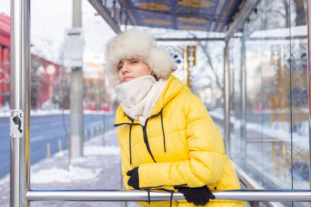 寒冷在寒冷的日子里 一个穿着冬衣的女人在公共汽车站等公共汽车漂亮肖像脸
