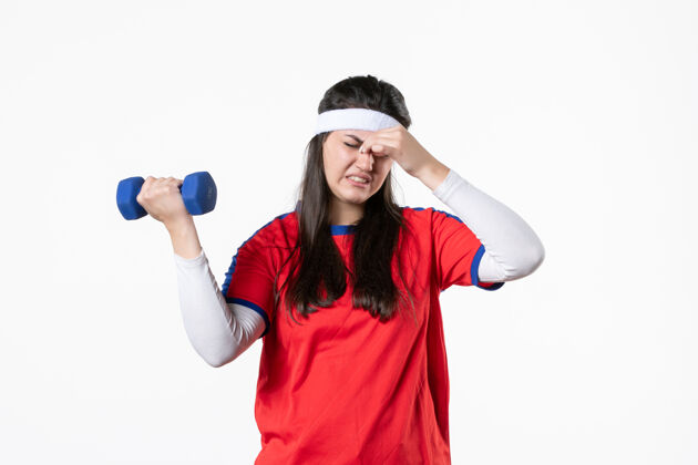 前面正面图疲惫的年轻女性穿着运动服 用哑铃锻炼身体白色运动女性