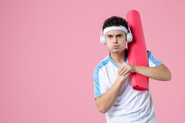 身体正面图强壮的年轻男性穿着运动服 带着瑜伽垫运动锻炼成人