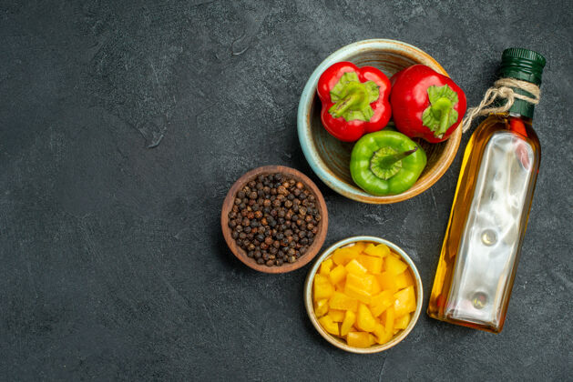 餐桌顶视图的甜椒碗在右侧与草药和蔬菜碗油瓶在一边的绿色桌子上胡椒素食西红柿