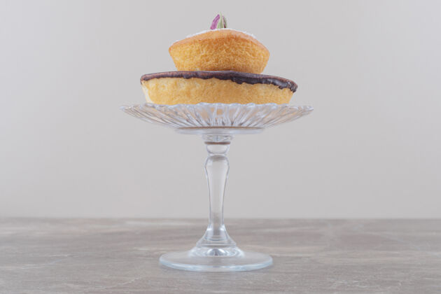 顶部巧克力蛋糕和香草粉蛋糕堆在大理石的玻璃基座上糕点烘焙香草