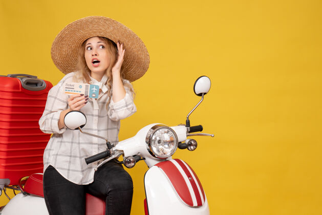 摩托车专心的年轻女子戴着帽子 坐在摩托车上 拿着车票听着黄色的最后一句闲话八卦最后轮廓