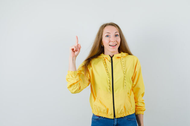 女人穿着黄色棒球服和蓝色牛仔裤的年轻女子用尤里卡手势举起食指成人目录年轻