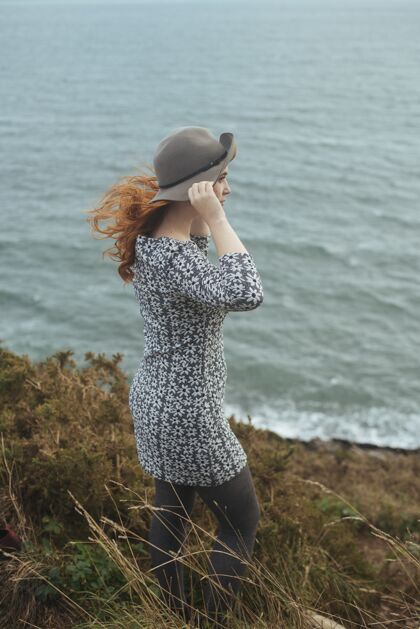 成人垂直拍摄一个戴着帽子的女人与大海绿色风海洋