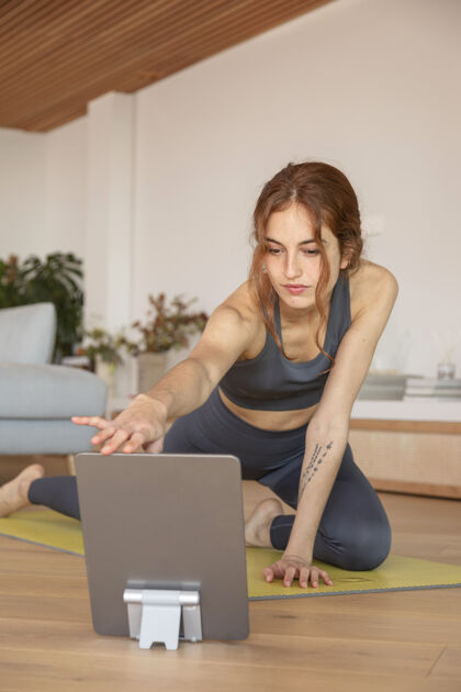 平板电脑女人在家做健身垫设备练习年轻人