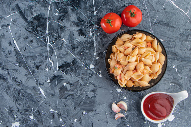 食物黑碗美味的海贝面食和番茄酱在大理石表面面食香肠番茄