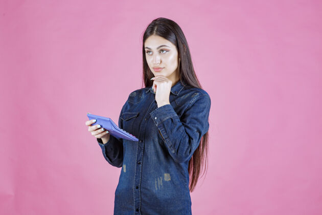 聪明拿着蓝色计算器思考的年轻女子工人数学金融