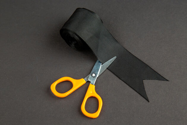 钥匙前视图黑色蝴蝶结用剪刀在深色表面上颜色深色衣服缝纫编织黑色蝴蝶结物体正面