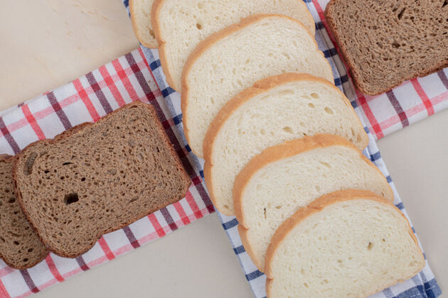 食品把新鲜的白棕色面包片放在桌布上烘焙硬皮皮