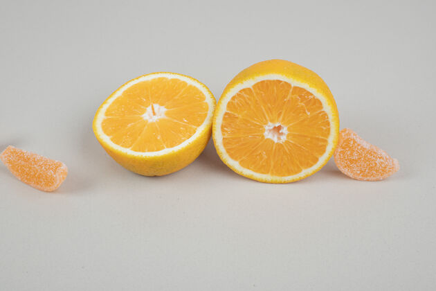 新鲜橘子片和果冻糖在米色的表面明胶美味零食
