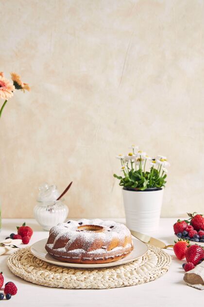 自制垂直拍摄的一个环形蛋糕与水果和粉末上的白色桌子与白色蛋糕巧克力鲜花