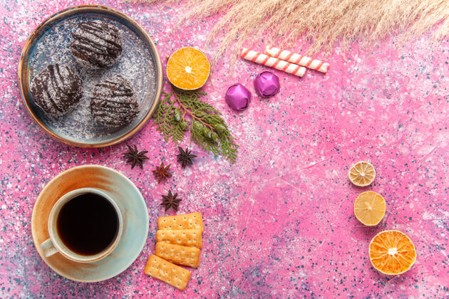 咖啡粉红色桌子上的巧克力蛋糕和一杯茶水果饼干茶