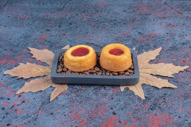 烘焙把果冻蛋糕和咖啡豆放在抽象桌上的小托盘里可口美味糕点
