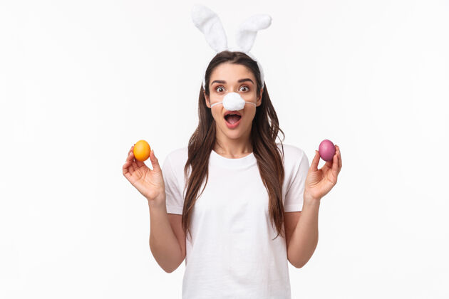 折扣肖像富有表现力的年轻女子戴着兔子的耳朵和鼻子 手里拿着彩蛋头发表情庆祝