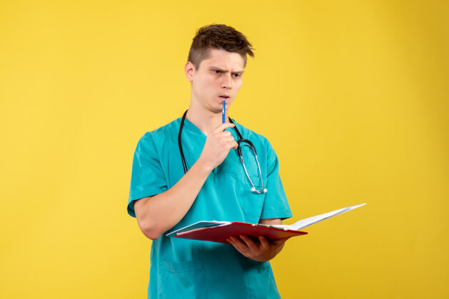 西装黄色墙壁上穿着医疗服的男医生手持分析图的正视图医院分析健康