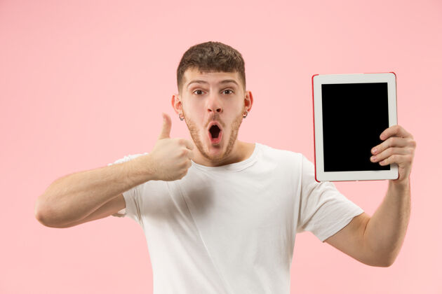 持有微笑的人指着笔记本电脑的肖像 白色屏幕上的空白隔离电脑男帅
