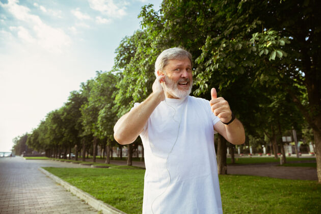 臂章高级男子作为跑步者 在城市街道上使用健身高加索男模在夏季早晨慢跑和有氧训练时使用小玩意健康的生活方式 运动 活动理念健康活跃退休
