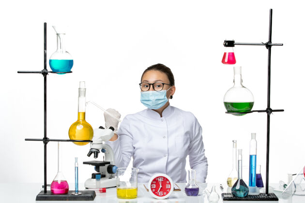 医学前视图穿着白色医疗服的女化学家带着面罩坐在白色背景上的溶液化学家病毒covid-飞溅实验室医学西装解决方案