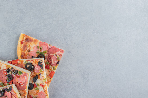 快餐美味的披萨片包在大理石上橄榄香肠切片