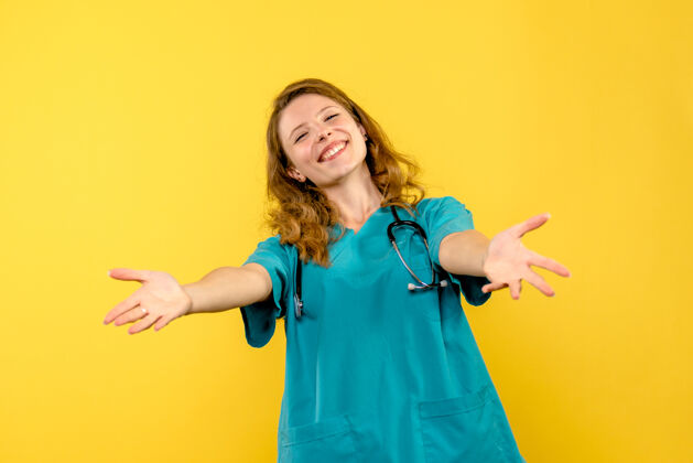 快乐正对着黄色墙上微笑的女医生医学职业保健