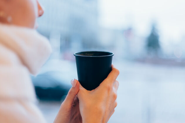 桌子一个女孩在舒适的咖啡馆里用一杯热咖啡取暖咖啡店街道冬天
