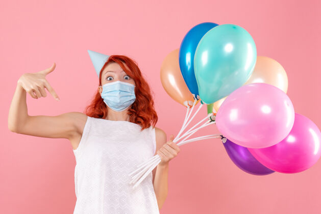 流行正面图年轻女性手持彩色气球在粉红色的面具上年轻女性气球丝带