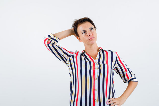 成熟成熟的女人手放在腰上 一只手放在头上 穿着条纹衬衫 神情沉思 俯瞰前方白发姿势衬衫