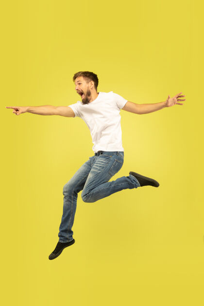 牛仔裤黄色背景上孤立的快乐跳跃人的全长肖像穿着休闲服的白人男模自由选择 灵感 人类情感概念指向 选择运动肖像情感