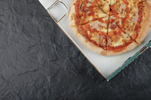 小吃在黑色表面的纸箱里放一个辛辣的水牛鸡肉披萨酱汁辛辣奶酪