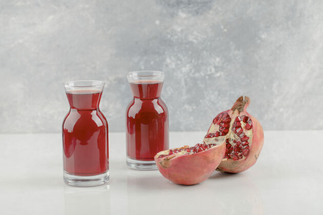 果汁白桌子上有红色的新鲜石榴和新鲜果汁整体新鲜天然