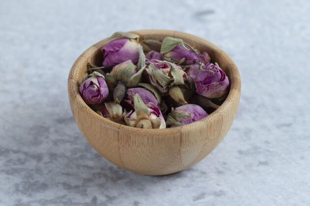 排毒粉红红色的干玫瑰花蕾放在一个木碗里 花瓣放在石头上芳香疗法草药松散