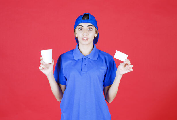 人类身着蓝色制服的女服务人员端着一杯饮料 递着名片 脸上露出惊讶的表情咖啡人一次性