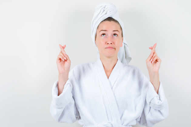 女性年轻的女士在白色浴衣 毛巾和手指交叉看起来周到 前视图女人健康健康
