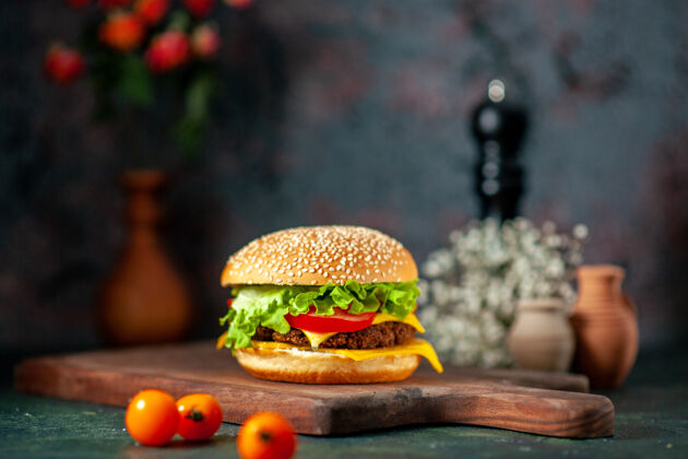 深色前视图肉汉堡包与新鲜西红柿在黑暗的背景肉奶酪芝士汉堡