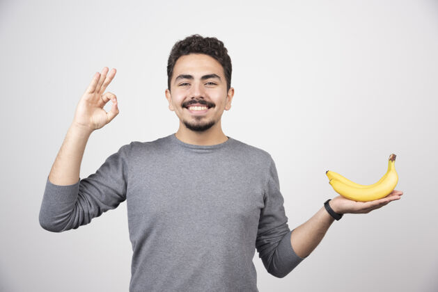 水果黑发男性拿着香蕉 并给出“确定”的手势快乐男孩姿势