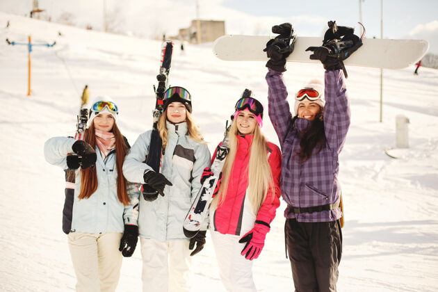 山腰女孩们手里拿着滑雪用具滑雪服上鲜艳的颜色女孩们在一起玩得很开心夹克休闲冬天