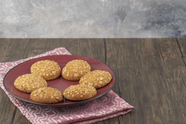 燕麦片红盘子里放满了燕麦片饼干 里面有种子和麦片放在木桌上小吃新鲜的燕麦片饼干