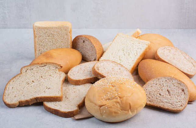 黑麦面包片和芝麻包在纸上面包石头切割