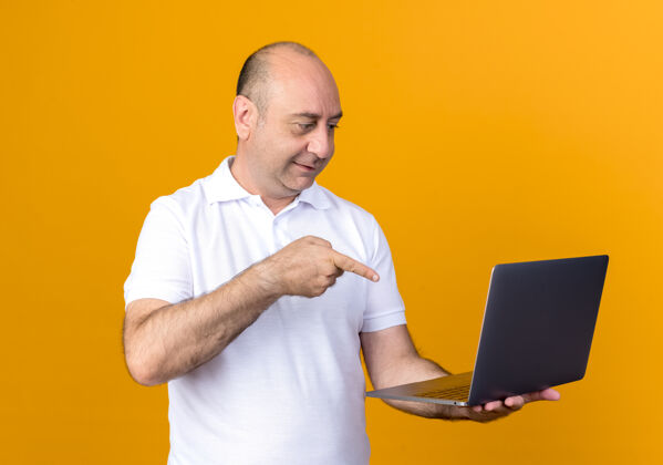 笔记本电脑喜欢随意的成熟男人拿着笔记本电脑指着隔离在黄色背景上成熟点请
