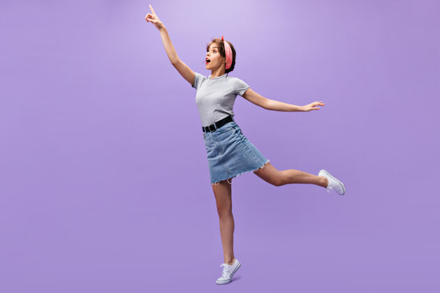 休闲快乐的女人在灰色t恤和裙子摆姿势n孤立的背景迷人可爱的女孩在夏天时尚的服装跳跃时尚女性紫色