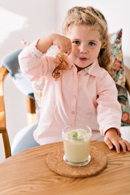 孩子一个快乐的小女孩 卷发 穿着粉色衬衫 在咖啡馆里吃着绿色的香烟人类头发女孩